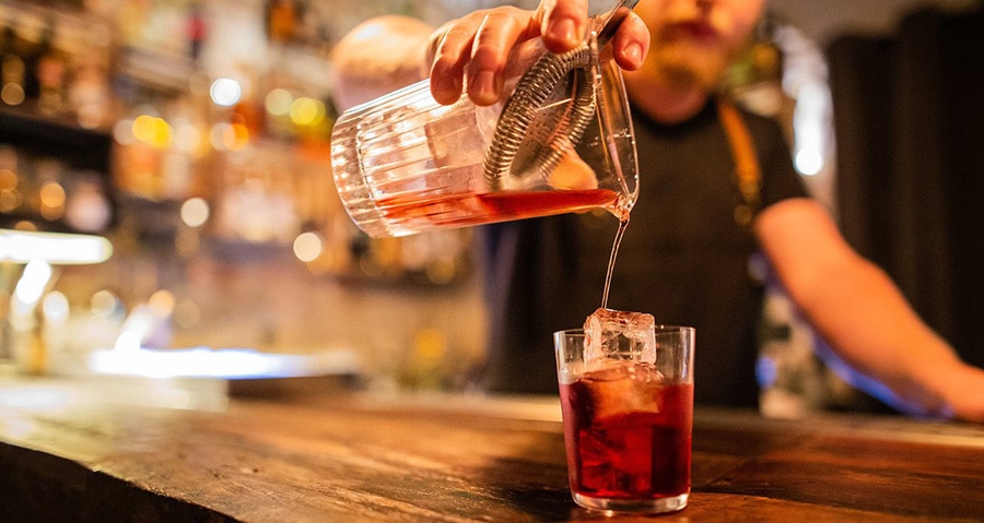 gloworder-image-of-bartender-pouring-negroni-into-glass-on-bar